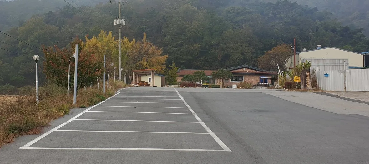 넓은 식당 주차장과 뒤로 단풍 든 나무와 산