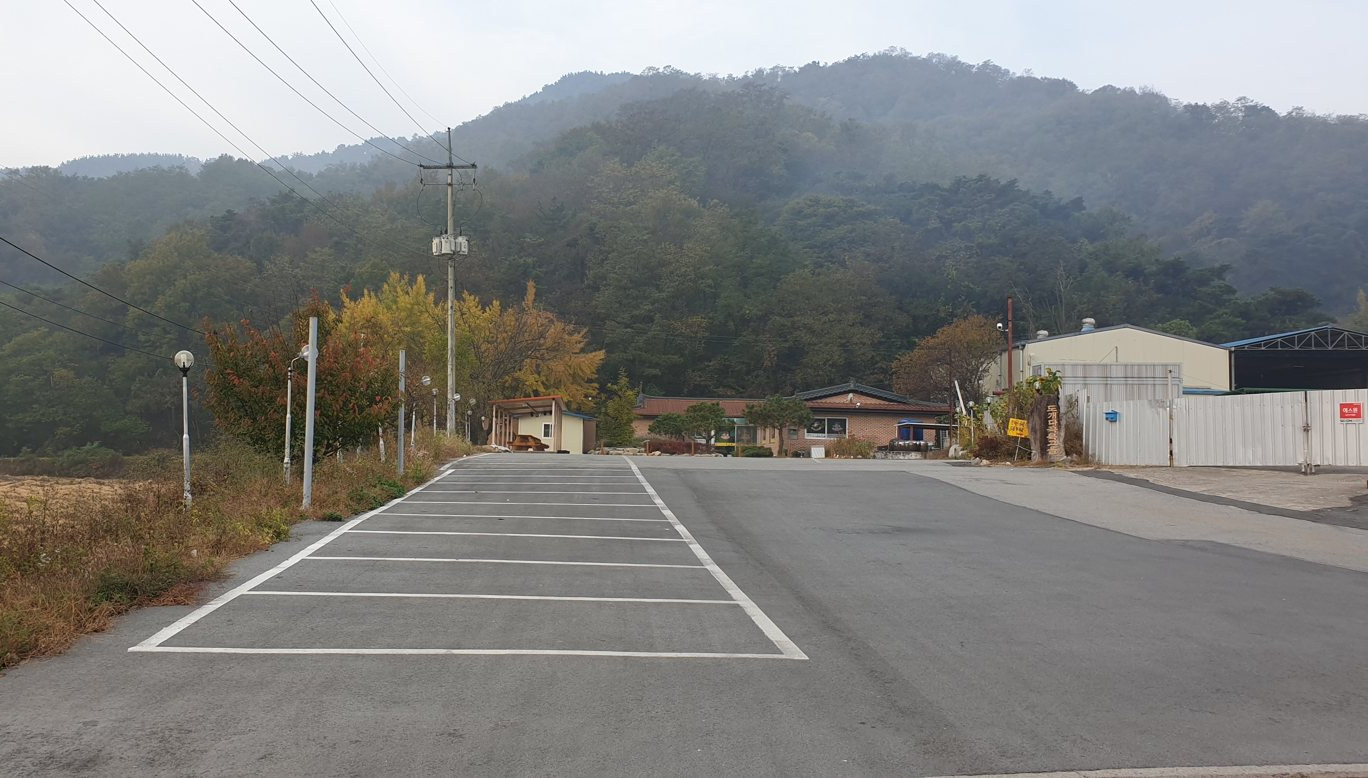 넓은 식당 주차장과 뒤로 단풍 든 나무와 산